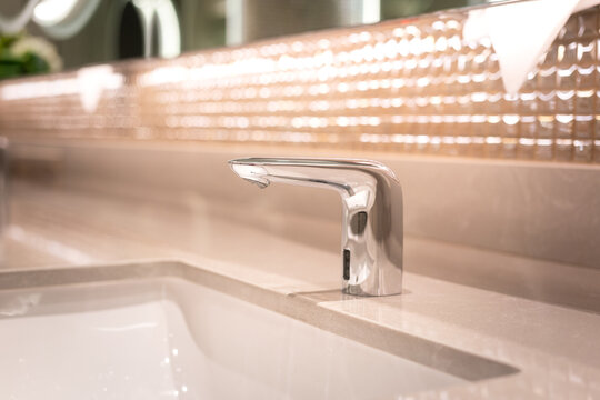 A luxury automatic hand washing faucet with background of . Interior equipment object photo, selective focus.