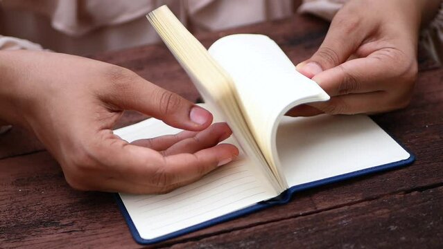 Close up of women hand turning a pager of a diary 