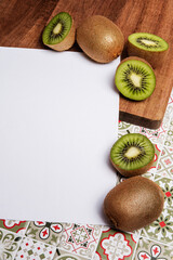 blank sheet with kiwi on wood table over green patterned tile background