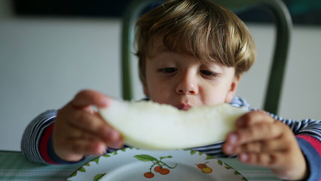 Child eating melon fruit hungry little boy eats healthy snack