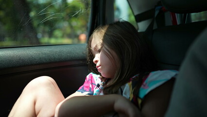 One bored little girl in car backseat waiting. Upset small child in boredom. Kid in traffic