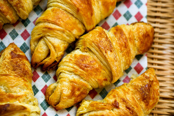 Basket of croissant bread on checkered tablecloth