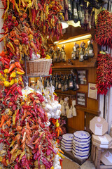 Fototapeta premium Palma de Mallorca, Spain - 7 Nov, 2022: Strings of red and yellow chilli peppers hanging in a grocery store