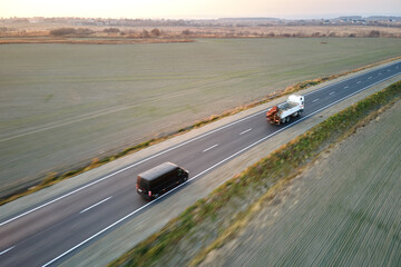 Aerial view of intercity road with fast driving cars at sunset. Top view from drone of highway traffic in evening