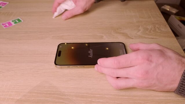 closeup modern gadget apple in male hands, testing new gold smartphone iPhone 14 Pro Max, wipes Super Retina display, care for gadget, Mobile device voice communication, Frankfurt - December 2022