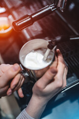barista heating fresh milk for making cappuccino or latte coffee hot drink
