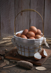 Chicken eggs in a basket on wood background.