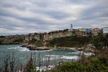 Fototapeta na wymiar distance lighthouse and town by the shore on a cloudy day 