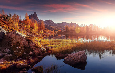 Inckredible autumn landscape during sunset. Fairy tale moutain lake with picturesque sky, majestic rocky mount and colorful trees glowing sunlight. Amazing nature scenery. Federa lake. Dolomites Alps
