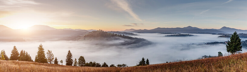 Incredible nature scenery im mountain. Beautiful natural landscape in the summer sunrise. Mountain valley with morning fog, colorful sky and visible silhouettes of Mountain ranges. Carpathian. Ukraine
