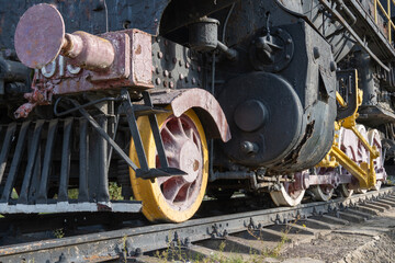 Close-up drive wheels and rods on steam engine locomotive. Vintage part of suspension of old train. Detailes rarity railway transport - lever and chassis, axle and connection. Parts rail.