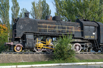 Fototapeta na wymiar Monument old soviet locomotive. Rarity transport of communism. Steam engine train from second world war stands on pedestal in city park. Inscription says - USSR and forward on west. Dnipro Ukraine.