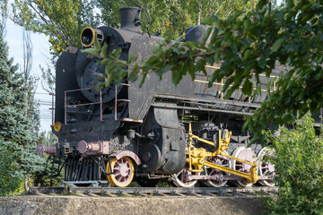 Monument old soviet locomotive. Rarity transport of communism. Steam engine train from second world war stands on pedestal in city park. Inscription says - USSR and forward on west. Dnipro Ukraine.