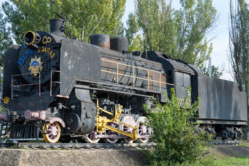 Monument old soviet locomotive. Rarity transport of communism. Steam engine train from second world war stands on pedestal in city park. Inscription says - USSR and forward on west. Dnipro Ukraine.