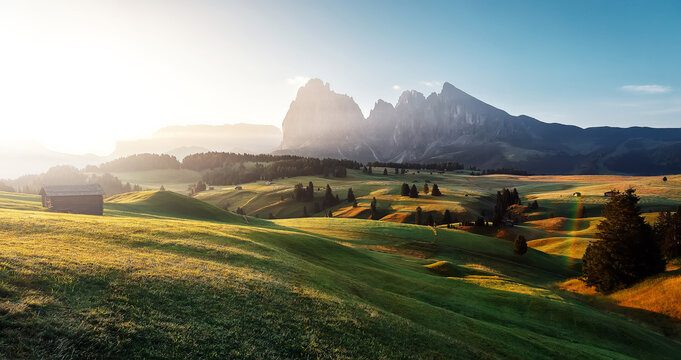 Fabulous mountain landscape in the Italy Alps with blooming meadows, rocky mountains in misty morning. Stunning wild nature image. Amazing natural summer scenery. Alpe di Siusi in sunrise, Dolomites