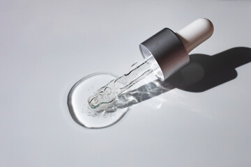 Transparent gel liquid with air bubbles and glass pipette on white background. Flat lay, top view, copy space.