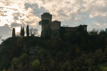 Fototapeta na wymiar shadow of a old castle with some people up the wall with sky and clouds in the background