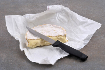 Coulommiers entamé avec un couteau en gros plan sur fond gris