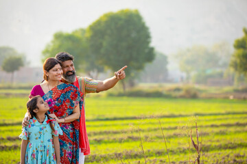 Indian farmer with wife and daughter at agriculture field.
