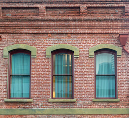 Fototapeta na wymiar Victorian Style Red Brick Building with Arched Windows and Green Facade