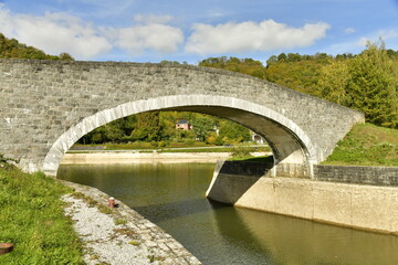 Fototapeta na wymiar Le petit pont en pierres enjambant le canal d'accès au port de plaisance d'Anseremme au sud de Dinant 