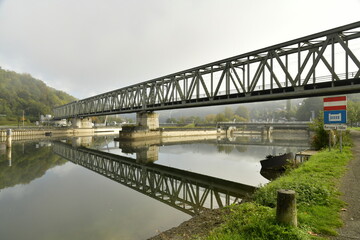 Fototapeta na wymiar Le pont du chemin de fer enjambant la Meuse sous la brume à Anseremme au sud de Dinant 