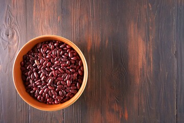 Dry raw red beans in a bowl on wooden background, top view.