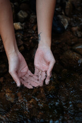 A young female cyclist is washing her hands by the creek