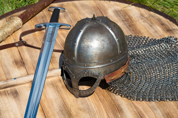 Helmet of norman type (Viking helmet) and Scandinavian sword lie on a wooden shield