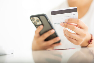 Close up shot of female hand holding credit card and using smartphone for online shopping