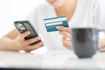 Close up shot of female hand holding credit card and using smartphone for online shopping