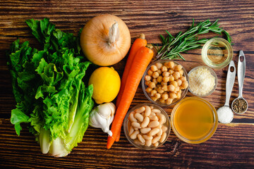 Nourishing White Bean and Lemon Soup Ingredients on a Wooden Table: Beans, vegetables, and other ingredients for soup on a rustic background