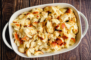 Torn Challah Bread in a Ceramic Baking Dish: Overhead view of pieces of torn bread in a rectangular baking pan