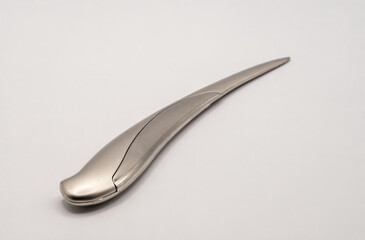 a shiny chrome plated steel knife letter opener standing upright in a clear glass jar