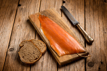 smoked salmon with sliced bread over cutting board - 555718461