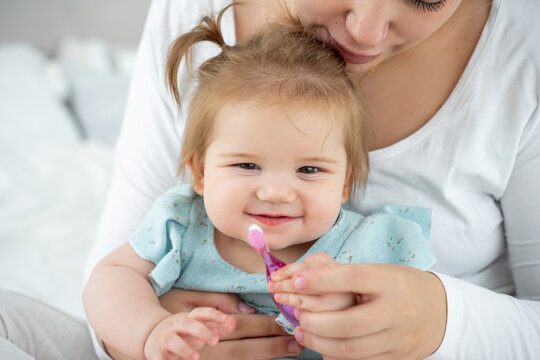 First knowledge of baby with toothbrush. Mom showing to child girl how to brush teeth. Habit of daily dental oral hygiene for children.