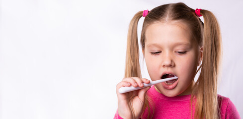 Beautiful little girl with blond hair brushes her teeth with a toothbrush