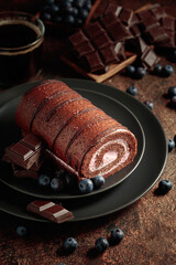 Chocolate roll cake with blueberries and a broken chocolate bar.