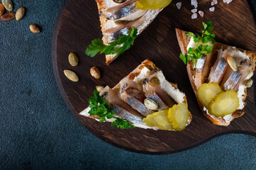 Toasts with bread, herring, pickled cucumber and cream cheese. Smorrebrod with herring. Danish food. Sandwich with herring. Healthy breakfast
