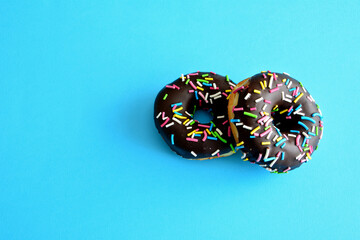 chocolate donuts with sugar sprinkles isolated in blue background, close-up