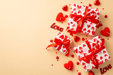 Valentine's Day concept. Top view photo of present boxes in wrapping paper with heart pattern candies inscriptions love candles and sprinkles on isolated pastel beige background with empty space