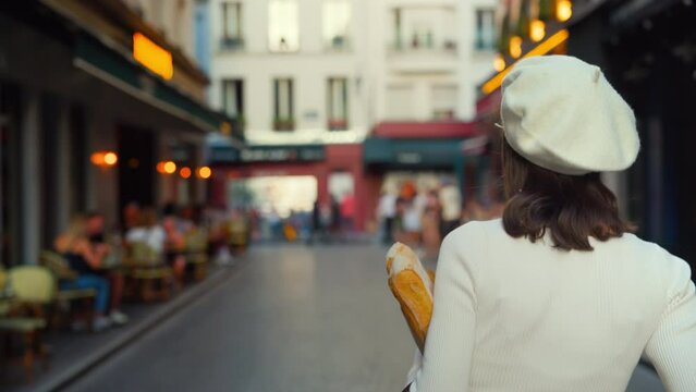 Beautiful girl walking down French street with baguettes and looking at camera