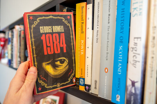 Calgary, Alberta - December 22, 2022: Pulling Orwell's 1984 off a bookshelf.
