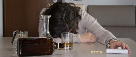 Image of a young woman passed out on the table after abusing alcohol and psychotropic drugs. Reference to the abuse and dependence of these substances. Horizontal banner 
 - obrazy, fototapety, plakaty