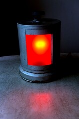 An old lantern with a red light on the table