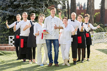 restaurant staff standing together and showing their thumbs up