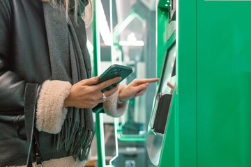 Close-up of a woman paying at a self-service machine using a contactless phone payment. Woman take...
