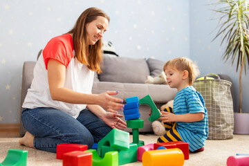 Kid and child development specialist playing together with colorful blocks