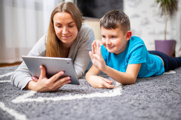 Happy mother and son greeting online looking at web camera using tablet pc