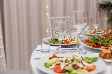 Served for holiday banquet restaurant table with dishes, snack, cutlery, wine and water glasses.